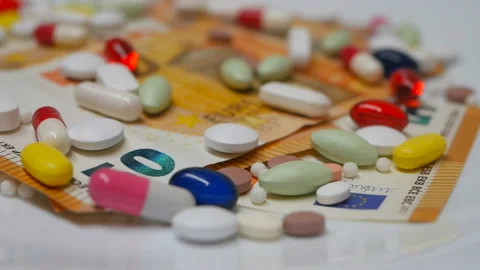 Close up, with red, white, colored pills rotating on 50s euro banknotes on white Stock Footage 86177076
