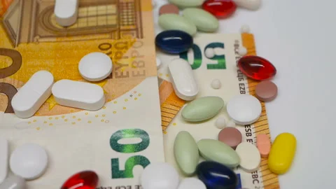 Close up, with red, white, colored pills rotating on 50s euro banknotes from the Stock Footage 86177102
