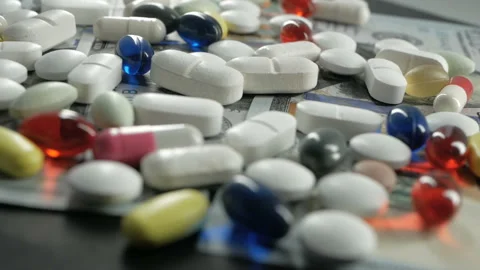 Close up, with red, white, colored pills rotating on dollars banknotes on black Stock Footage 91270102