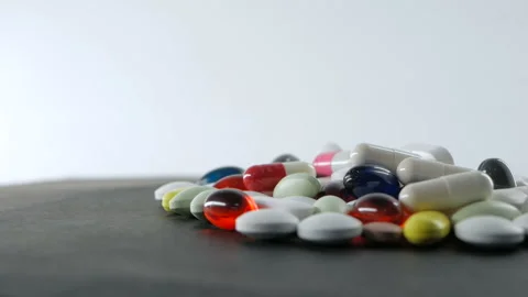 Close up, with red, white, colored pills rotating on white black backgrounds Stock Footage 91270618