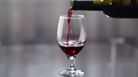 Close-up of red wine being poured from a bottle into a glass, rack focus Stock Footage 135823974