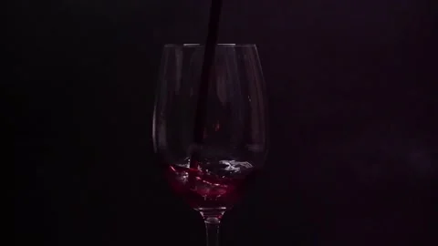 Close-up of red wine being poured into glass against dark background Stock Footage 170790359