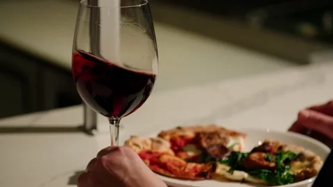Close up red wine swirled in slow motion with pizza in background, 4K Stock Footage 229808900
