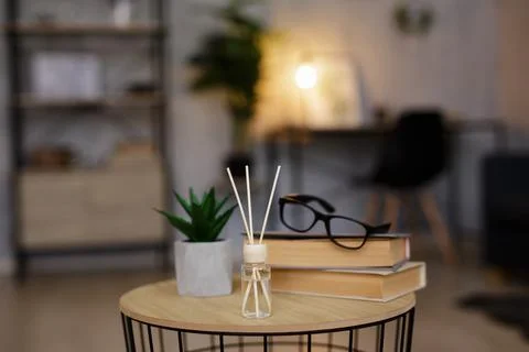 Close up of reed diffuser, books, glasses and house plant on the table in liv Stockfoto's