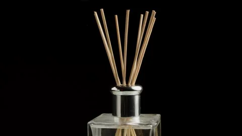 Close-Up of reed diffuser sticks in glass bottle against black background Stock Footage 348596012