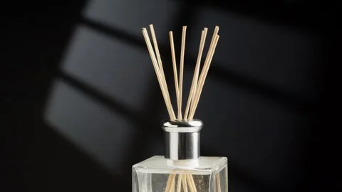 Close-Up of Reed Diffuser Sticks in Glass Bottle Against Dark Background Stock Footage 348596017