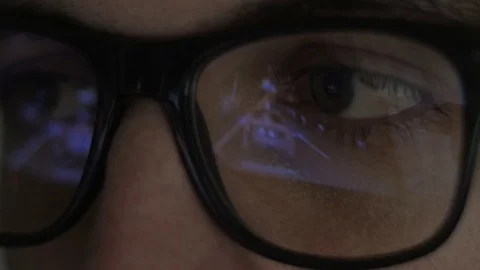 Close-up reflection in glasses: Gamer plays a video game on a computer in a dark Stock Footage 84743589