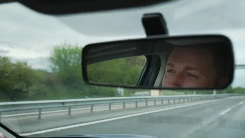 Close up, reflection of male driver in rear view mirror of car during trip. Stock Footage 308928913
