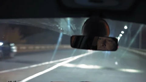 Close-Up, Reflection of Men in the Rearview Mirror of a Car Riding Through a Stock Footage 98468779