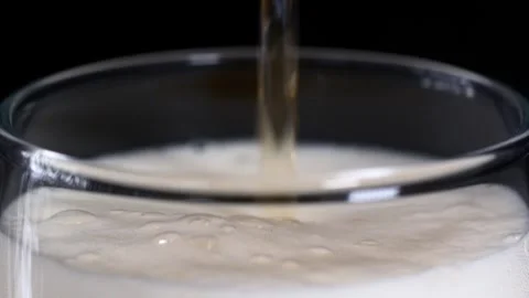 Close-up of refreshing beer being poured into a clear glass, forming rich Stock Footage 314793624