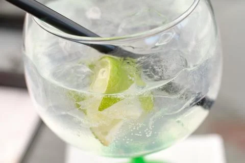 Close-up of a refreshing gin and tonic cocktail with lime wedges and ice cube Stock Photos