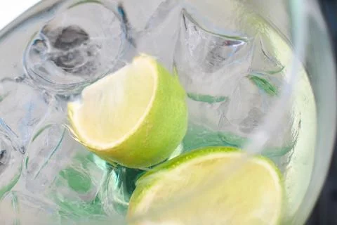 Close-up of a refreshing gin and tonic cocktail with lime wedges and ice cube Stock Photos