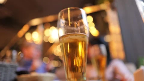 Close up of refreshing golden beer in glass with bokeh background and peopl.. Video stock 337334652