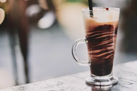 Close-up of a refreshing iced coffee beverage in a tall glass mug on a wood.. Stock Photos