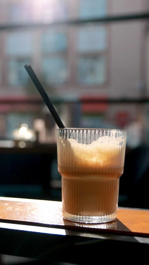 Close-up of a refreshing iced coffee drink in a ribbed glass with a straw o.. Video stock 341673144