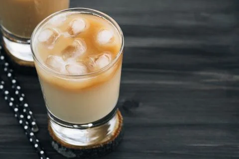 Close-up of a refreshing iced coffee with milk in glasses on a wooden black Stock Photos