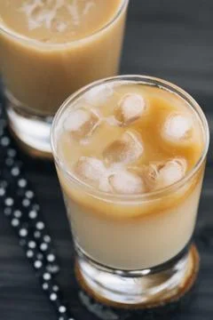Close-up of a refreshing iced coffee with milk in glasses on a wooden black Stock-Fotos