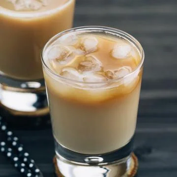 Close-up of a refreshing iced coffee with milk in glasses on a wooden black Stock-Fotos
