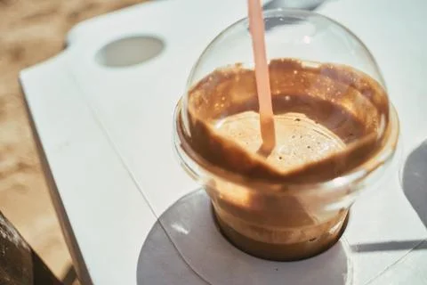 Close-up of a refreshing iced coffee in a plastic cup with a straw on a table Stock Photos