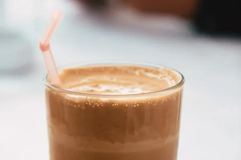 Close-up of a refreshing iced foamy coffee in a glass with a straw Stock Photos