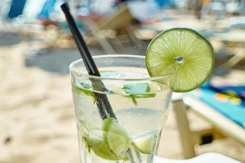 Close-up of a refreshing mojito cocktail with lime slices and mint on beach.. Stock Photos