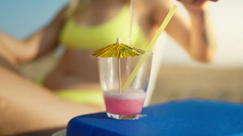 Close-up of refreshing pink drink with paper umbrella and straw on sandy be.. Stock Footage 341342239