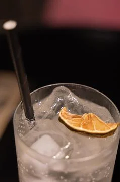 Close-up of a refreshing sparkling beverage with ice cubes, black straw and d Stock Photos