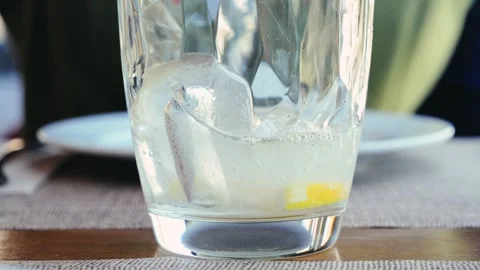 A close-up of refreshing sparkling water with a lemon wedge and ice cubes being Stock Footage 321950492