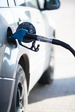 Close up of the refueling nozzle inserted into the petrol tank on blurred car Stock Photos