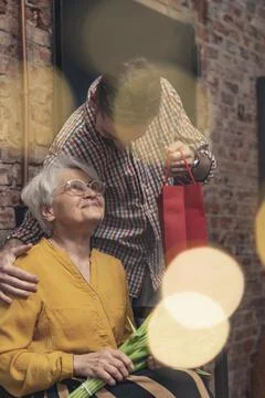 Close relationship between grey-haired retired grandma receiving a gift from her Stock Photos