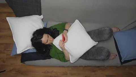 Close up of a relaxed girl using a smart phone lying on a sofa in the living Stock Footage 129382645
