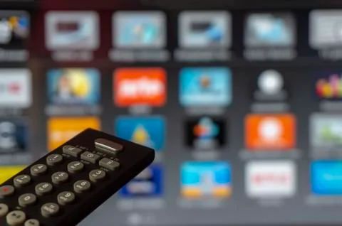 Close-up of remote control and watching smart tv Stock Photos