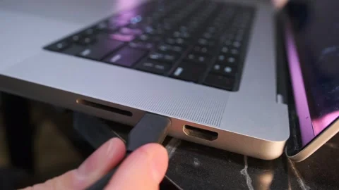 Close-up of removing a USB-C cable from a laptop port, showing device Stock Footage 333649435