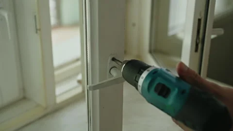 Close-up of repairman using screwdriver and drill to repair window handle during Stock Footage 310800022