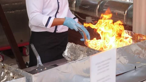 A close-up of a restaurant chef cooking on fire in an outdoor kitchen. Video stock 240472497