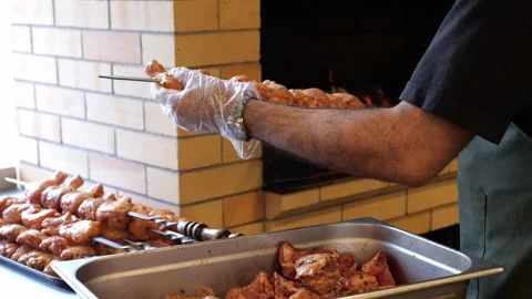 Close-up of a restaurant chef stringing chicken legs on a skewer before grilling Stock Footage 319431194