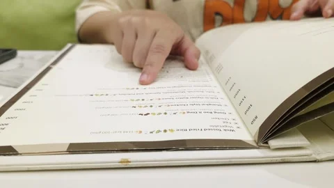 Close-up of a restaurant guest pointing at menu items while choosing a meal in Stock Footage 339210846