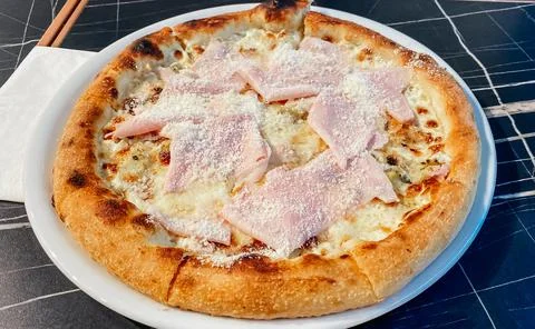 Close-up on a restaurant table pizza with prosciutto cotto and taleggio cheese Stock Photos