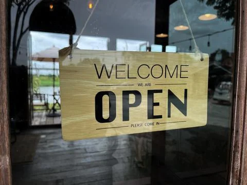 Close up of restaurant worker turning Open sign to reopen the cafe to welcome cu Stock Photos