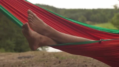 Close-up of a resting man's legs in an orange hammock Stock Footage 170907650