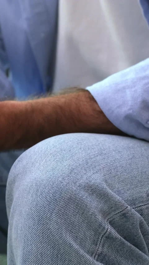 Close up of a restless man anxiously tapping his fingers on his knee, a subtle Stock Footage 344781489