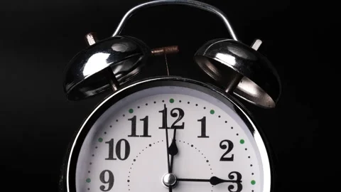 Close-up of a retro alarm clock face in time lapse on black background. Video stock 260682825