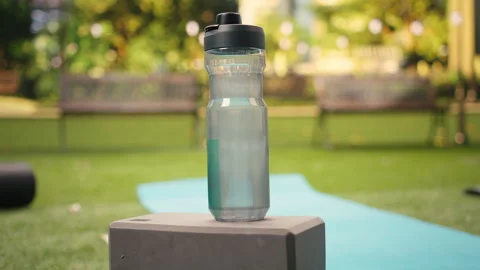 Close up of reusable water bottle on stacked yoga blocks beside yoga mat Stock Footage 346028530