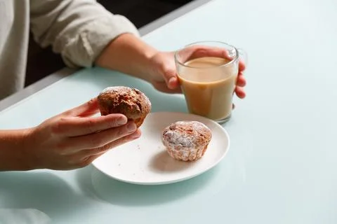 Close up of right hand taking one of two curd muffins from plate, and left .. Stock Photos