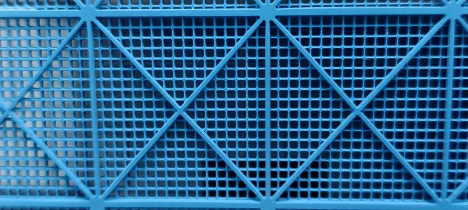 Close‑up of a rigid blue plastic grid featuring small square openings Stock Photos