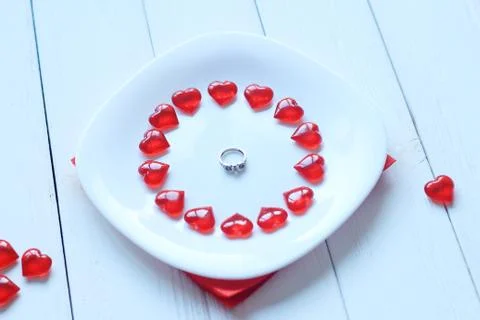 Close up.ring and red hearts on a white plate Stock Photos