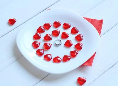 Close up.ring and red hearts on a white plate Stock Photos