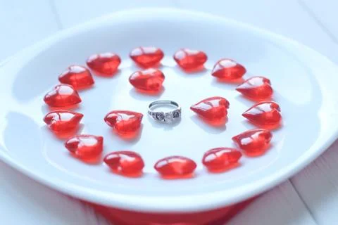 Close up.ring and red hearts on a white plate Stock Photos