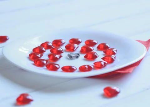 Close up.ring and red hearts on a white plate Stock Photos