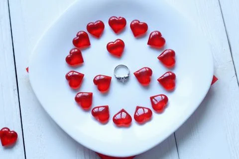 Close up.ring and red hearts on a white plate Stock Photos